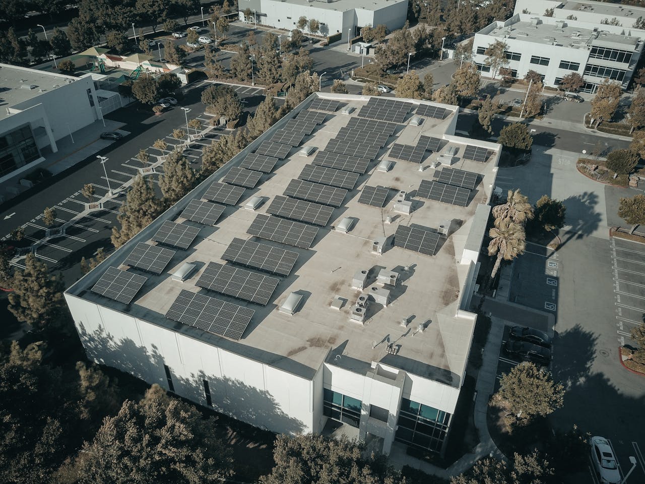 why-choose-us Aerial shot of a commercial building with solar panels, emphasizing renewable energy architecture.